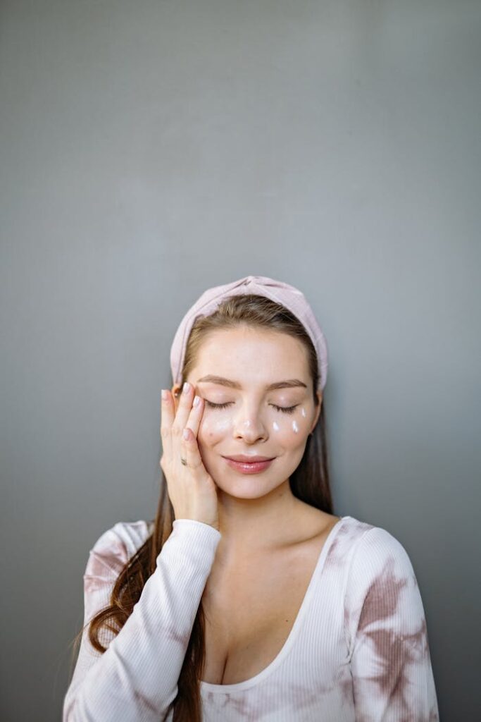 Caucasian woman enjoying skin care routine with cream on face and eyes closed, promoting self-care and beauty.